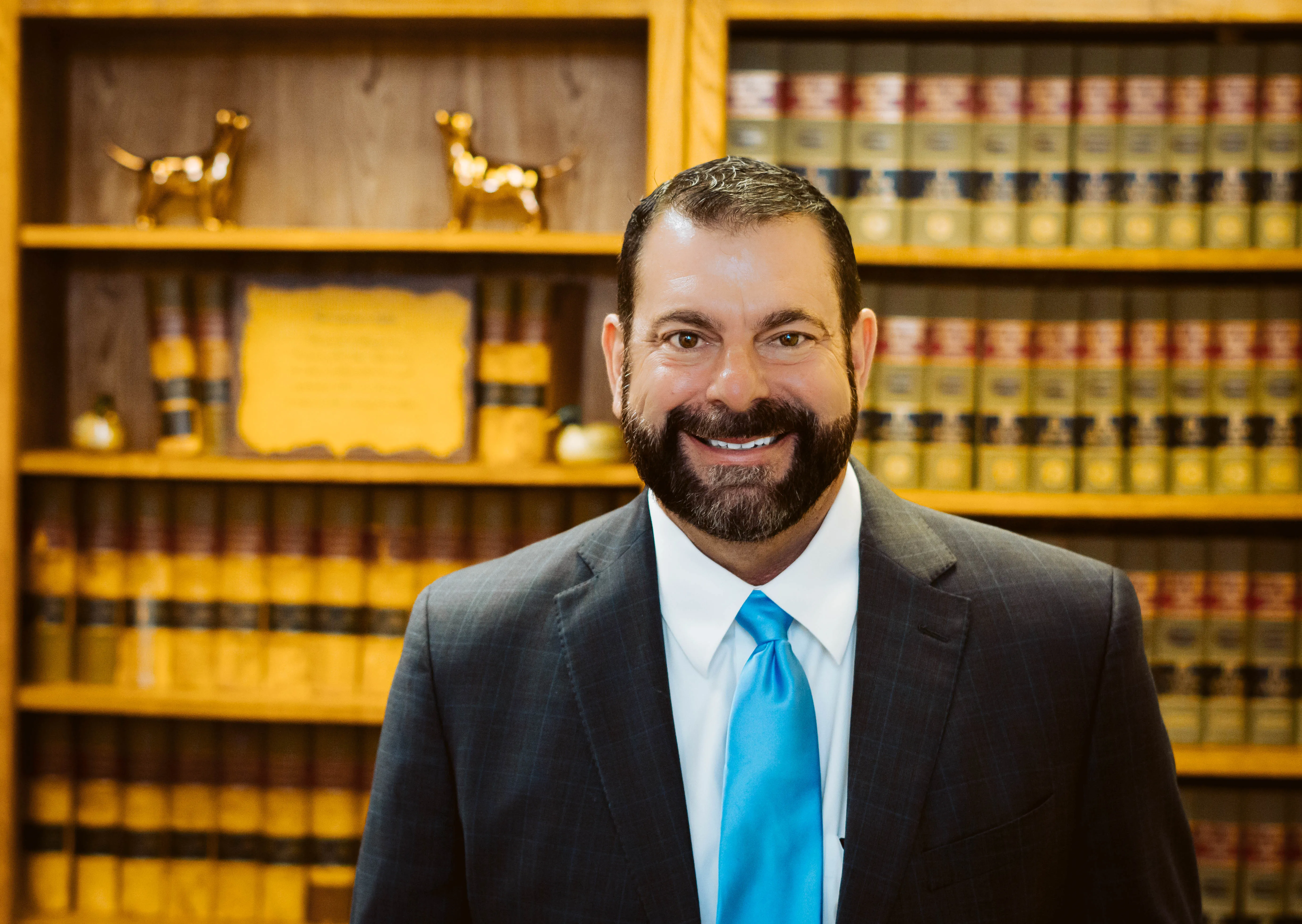 Cody Pirtle in suit looking at camera, bookcase as background.